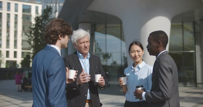 Medium shot of diverse business people have coffee break and talking outdoors downtown