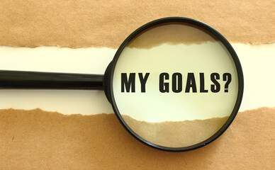 The magnifying glass reveals the MY GOALS text appearing behind the torn brown paper.