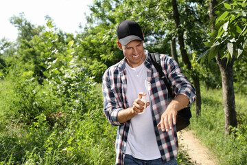 Man spraying tick repellent on arm during hike in nature