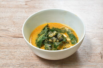 spicy boiled cockle with acacia and basil leaf in red curry coconut milk soup in bowl