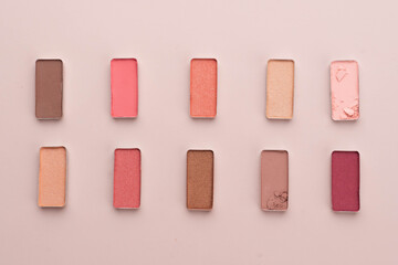 A broken eye shadow make up palette on a beige background. Beauty and cosmetic concept. Flat layout. Copy space.