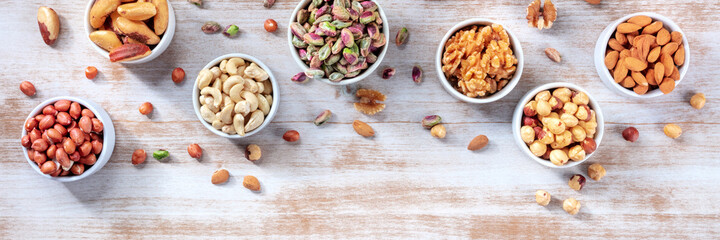 Nut panorama, shot from above with a place for text on a rustic wooden background. Healthy vegan snacks
