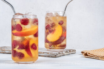 Delicious peach lemonade with soda water and raspberries. Fresh summer ice tea cocktail