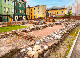 Ruins of medieval Saint Catherine church and vintage tenement houses in Bytow historic city center in Kaszuby region of Pomerania in Poland - obrazy, fototapety, plakaty