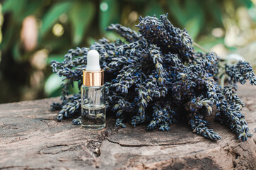 Natural essential oil of lavender. Bottle with lavender oil and a bouquet of fresh lavender on a wooden background. Skin care