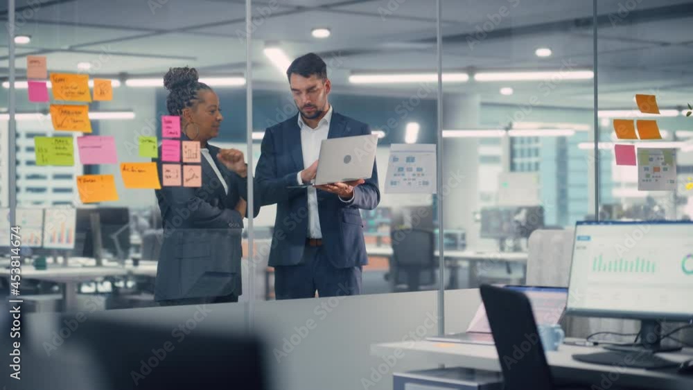 Poster young businessman talking with experienced colleague while using laptop computer in office. employee