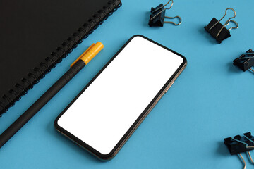 Smartphone with black notebook, pen on the white table. Mock up. 