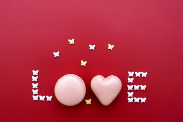 Word LOVE made of pink heart and round shape macarons and small butterflies. Sweets, love concept, greeting card, copy space for text