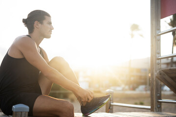 Fototapeta na wymiar Sporty athletic man exercises at the beach. Handsome man training outdoors..