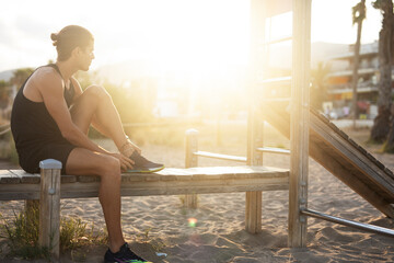 Sporty athletic man exercises at the beach. Handsome man training outdoors..