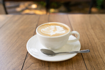 Latte coffee or cappuccino coffee in white cup with beautiful tree latte art on wooden table.