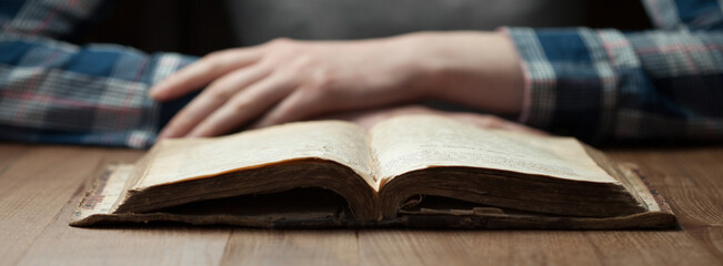 woman reading the bible in the darkness over wooden table. Bible is opened on a table