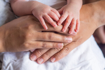 Close-up of newborn hands placed on mother and father hands on white cloth. Happiness parents. Love of family concept. Space for text