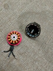 brushless motor, red and black with gray magnets and copper windings, lies on a gray sofa