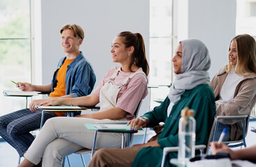 Group of multiethnic university students sitting in classroom indoors, studying.