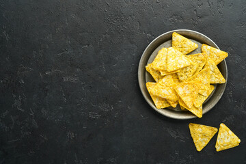 Nachos. Traditional latinamerican Mexican corn chips with guacamole dip sauce in a black bowl with...