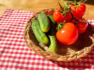 Red tomatoes and green cucumbers on a wooden background.Fresh vegetables top view with copy space for text. Flat lay. The concept of the harvest, vegetable garden.Natural products, agriculture. Layout