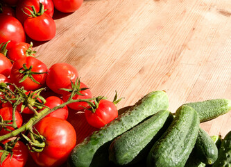 Red tomatoes and green cucumbers on a wooden background.Fresh vegetables top view with copy space for text. Flat lay. The concept of the harvest, vegetable garden.Natural products, agriculture. Layout