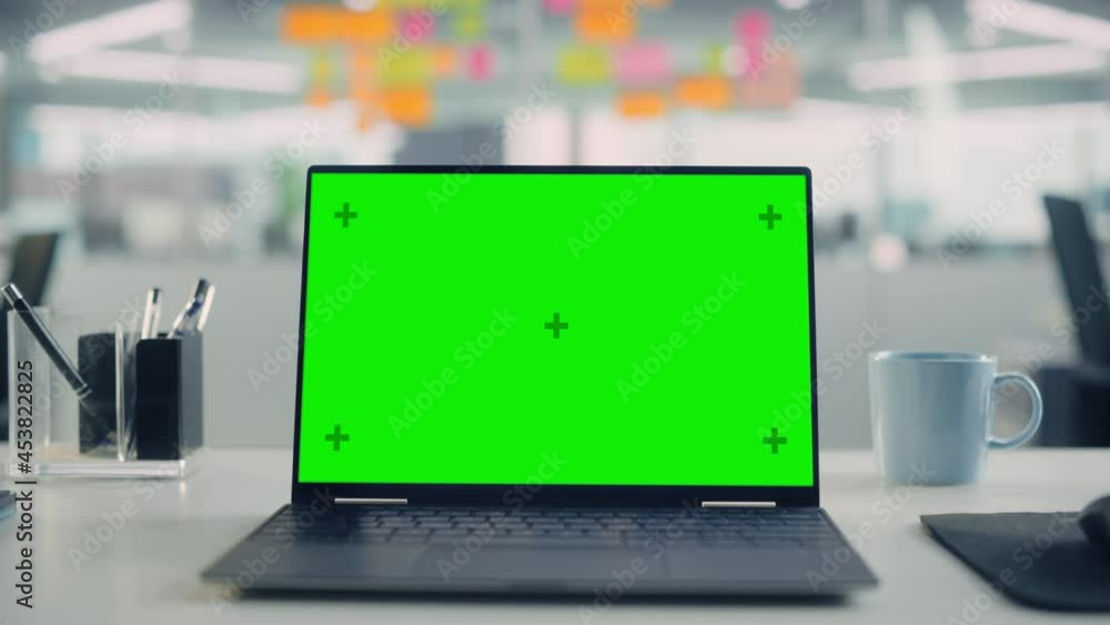 Fototapete Laptop Computer with Mock Up Green Screen Chroma Key Display Standing on the Desk in the Modern Creative Office. In the Background Glass Wall with Colorful Planning Notes. Zoom in Shot.
