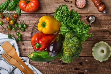 Fresh cherry tomato branches, basil leaves, napkin, pepper and pepper mill on old wooden rustic background. Food cooking background and mock up.