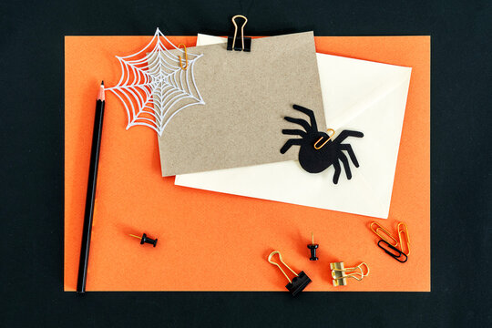 Autumn Fall Halloween theme desktop workspace with card, envelope, pencil, clips on stylish orange textured background.