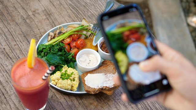 Top view of human hands taking pictures of a healthy plant based brunch with a smartphone