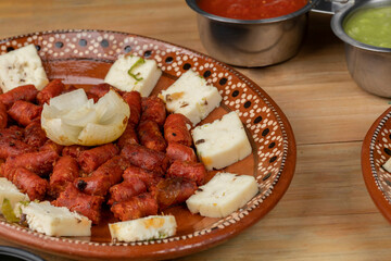 chistorra dish with cheese mounted on a clay plate accompanied by sauce. Mexican food