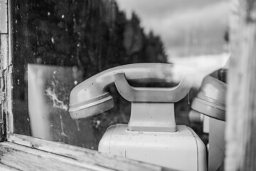 Grayscale of a vintage telephone behind the glass