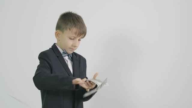 Little child in suit with bow hold money and play with banknote, money fly, businessman gives the blow, success dance, conceptual, slow motion
