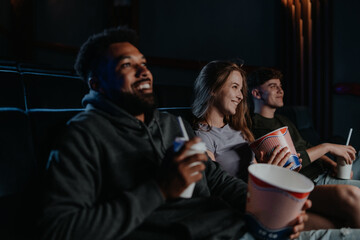 Cheerful young couple with popcorn in the cinema, talking.
