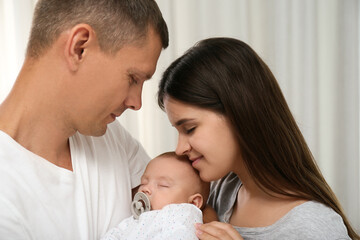 Happy family with their cute sleeping baby indoors