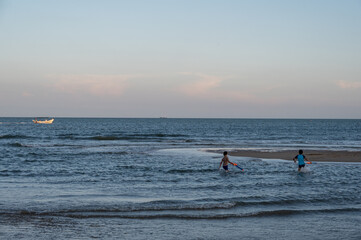 In the sea and beach after sunset, there were two children playing water