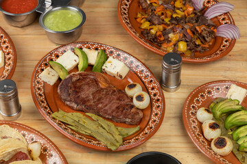 Mexican food, cut of meat served on a plate with nopal, avocado and onion on a wooden table