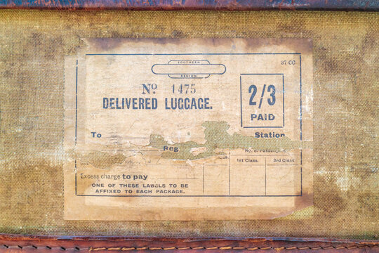 Vintage torn paper luggage label with text delivered luggage on an old suitcase