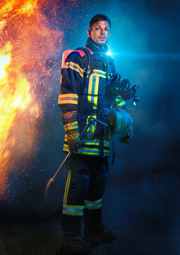 Feuerwehrmann steht vor Flammen und Blaulicht