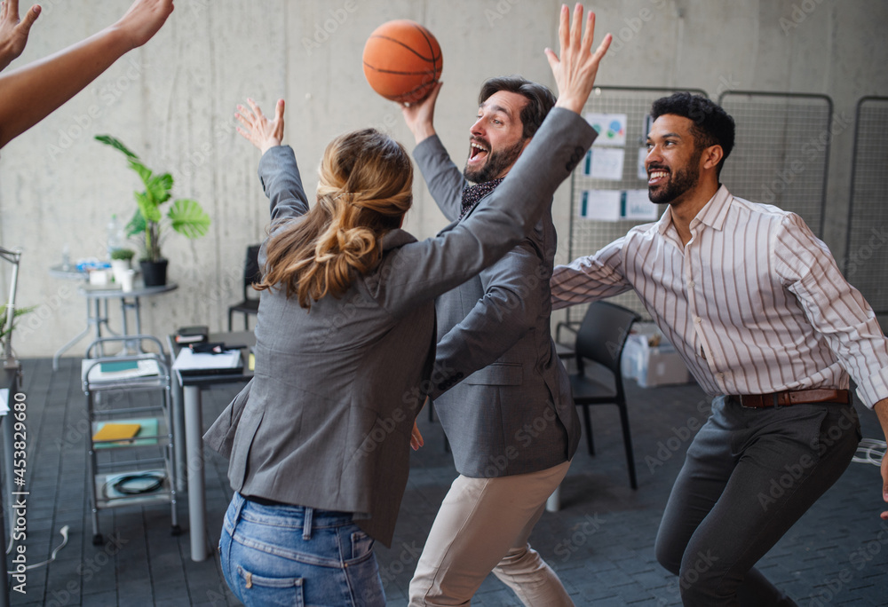 Wall mural group of cheerful young businesspeople playing basketball in office, taking a break concept.