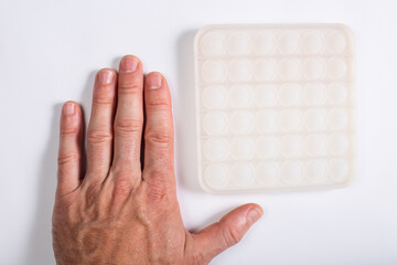 Antistress silicone toy. Trandy pop bubble toy. Adult hand with anti stress toy.