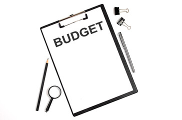 On a white background magnifier, a pen and a sheet of paper with the text BUDGET . Business concept