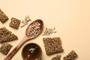 Pieces of delicious kozinaki bars, honey and sunflower seeds on beige background, flat lay. Space for text