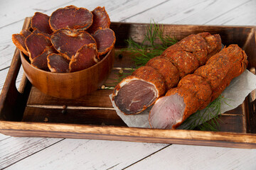 Homemade jerked dried meat or biltong with spices on a wooden background. Beer snack concept. Selective focus, copyspace.