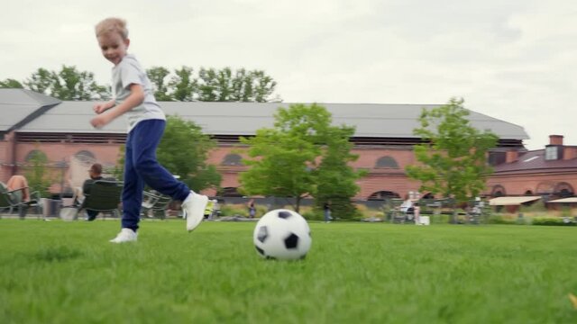 Active mother, father and little son with ball playing soccer at summer park