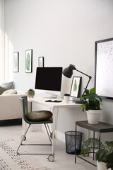 Comfortable workplace with modern computer and houseplants in room. Interior design