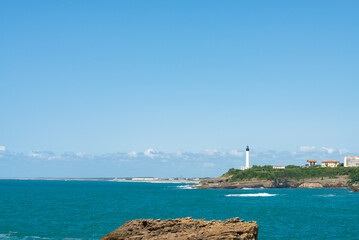The coastline of the famous Biarritz, France. Ocean waters in the foreground. Lighthouse on the...