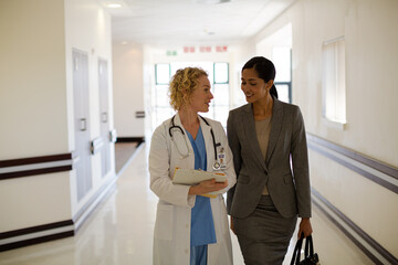 Doctor and businesswoman walking in hospital corridor