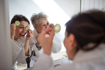 Happy senior mother in bathrobe with adult daughter indoors at home, selfcare concept.