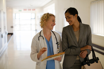 Doctor and businesswoman walking in hospital corridor
