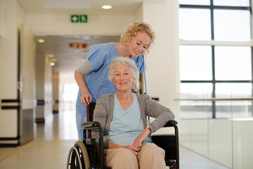 Fototapeta na wymiar Portrait of smiling nurse and elderly patient in wheelchair