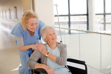 Obraz premium Portrait of smiling nurse and elderly patient in wheelchair
