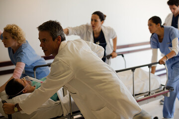 Obraz premium Doctors rushing patient on gurney in hospital corridor