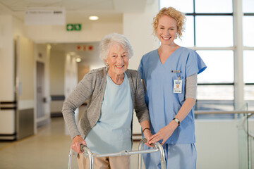 Nurse helping senior patient with walker in hospital corridor